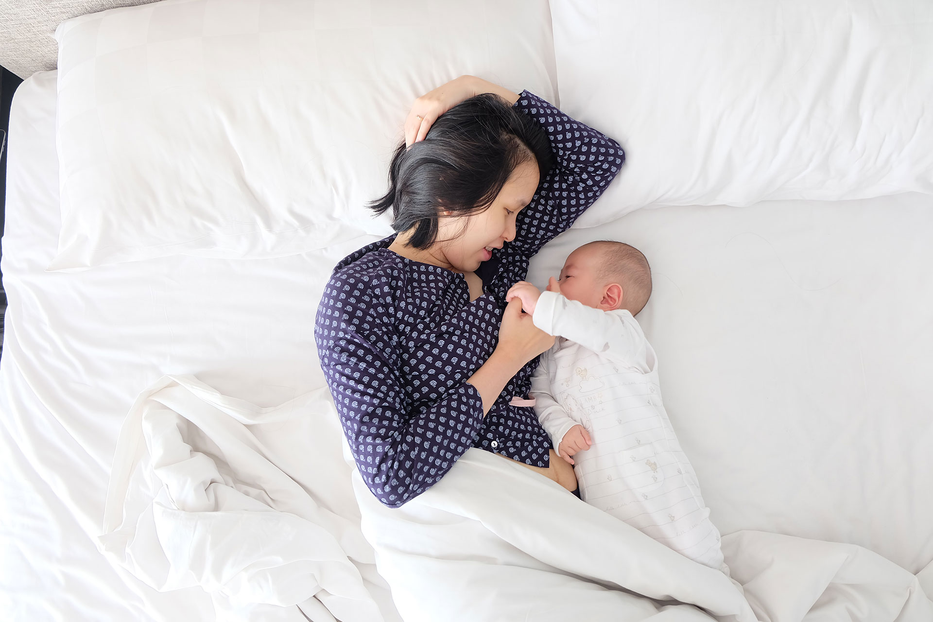 mother breastfeeding baby in bed